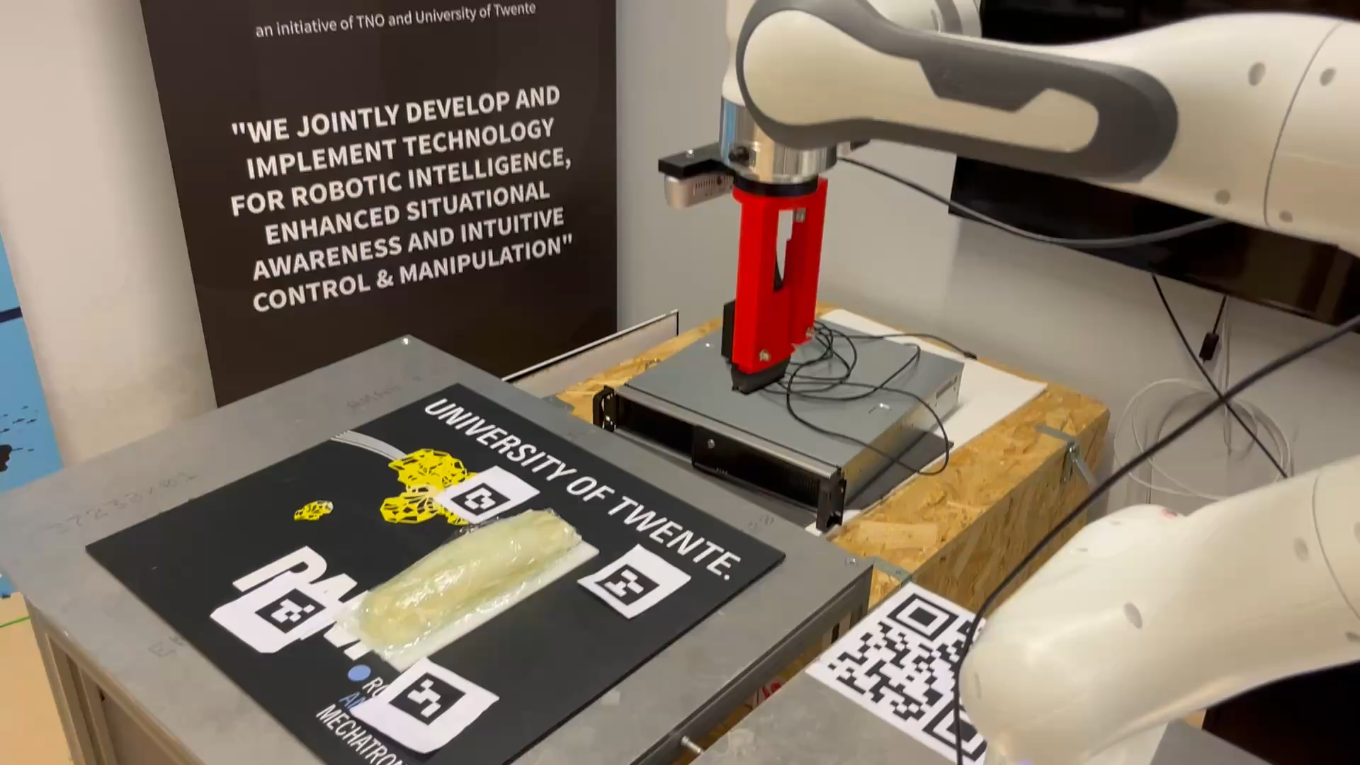 Laboratory robot and ultrasound probe beside a phantom on a University of Twente marker board.